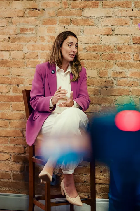 Daniella Mello in conversation against a brick wall at Serena